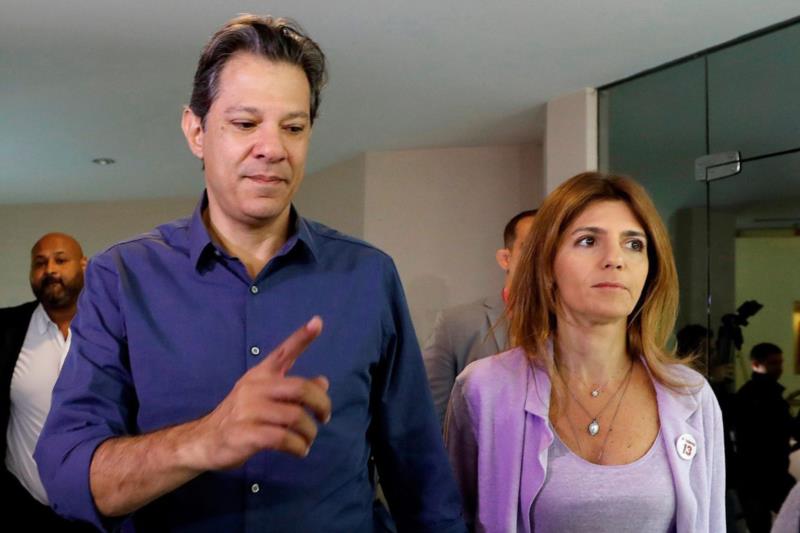 Com camisa azul, Haddad vota e faz sinal de vitória